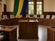 Plenário de câmara municipal vazio com tribuna de madeira e microfone em destaque